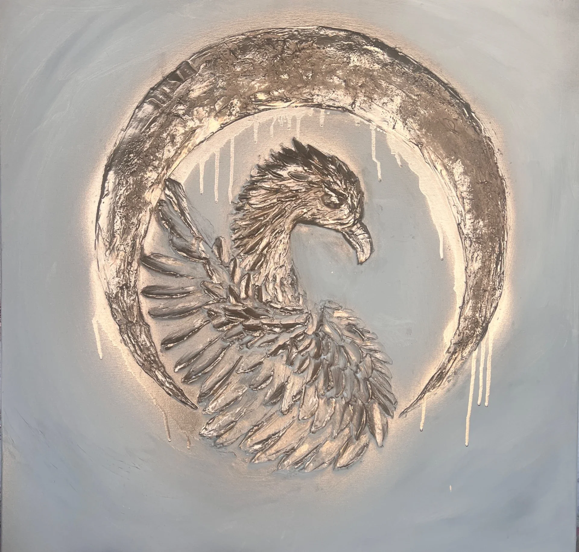 Metallic eagle emblem with a detailed eagle head and outstretched wings, encircled by a distressed metallic ring, on a light background.