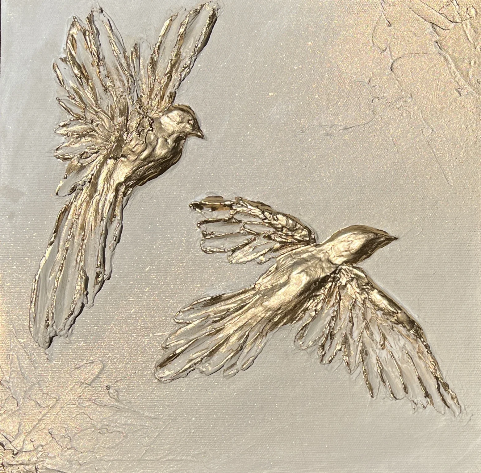 Silver embossed image of two flying birds with outstretched wings on a metallic surface.