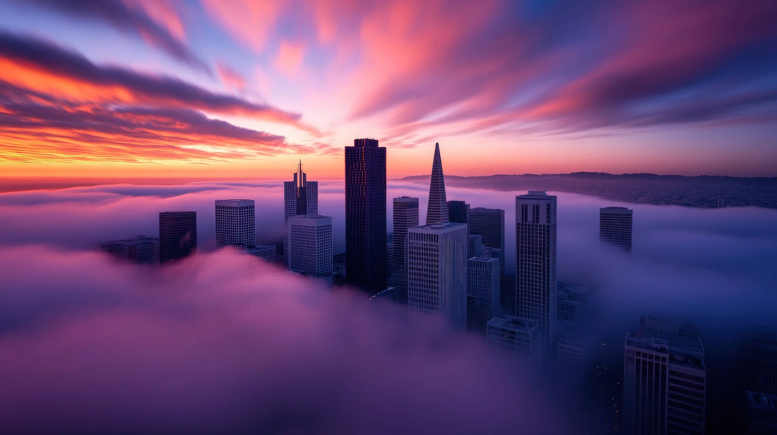 City skyline with skyscrapers emerging above fog, sunset sky with purple, pink, and orange clouds.