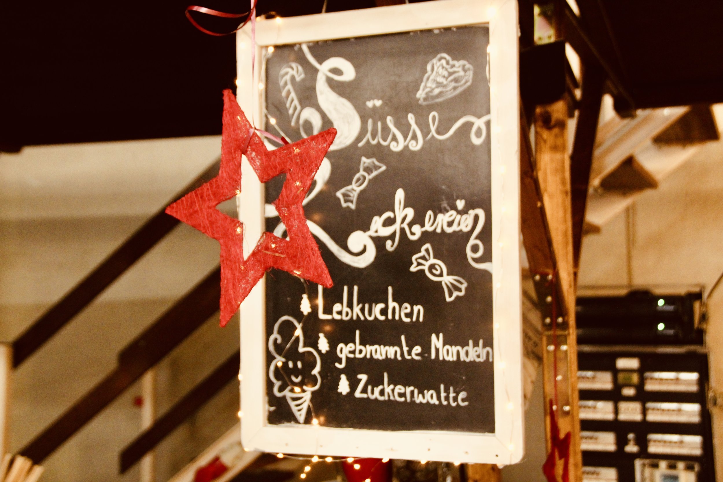 Tafel mit Weihnachtsgebäck, Lebkuchen, gebrannten Mandeln und Zuckerwatte, dekoriert mit einem roten Stern.