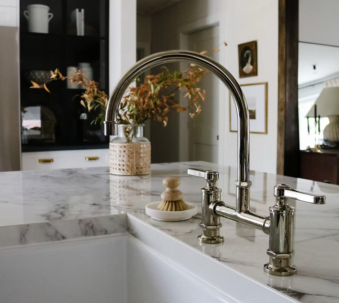 Kitchen sink with a marble countertop, chrome faucet, and a small dish with a brush