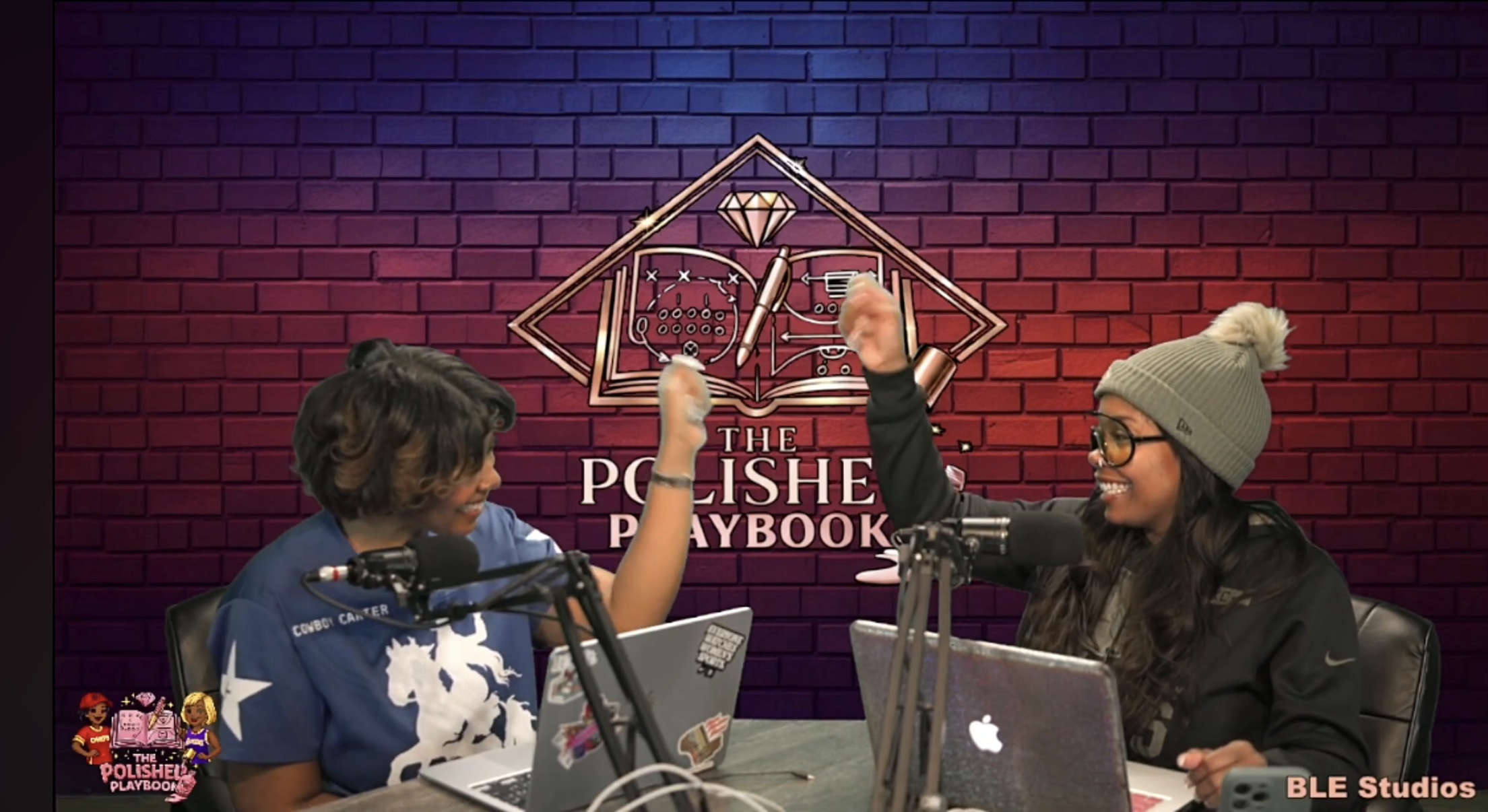 Two women are sitting at a table with laptops, smiling and giving a high-five in front of a brick wall background with the logo 'The Polished Playbook,' microphones are in front of them, and the woman on the right is wearing a gray beanie and glasses.