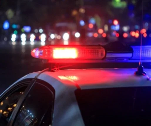 Close-up of a police car with its red and blue emergency lights flashing at night.