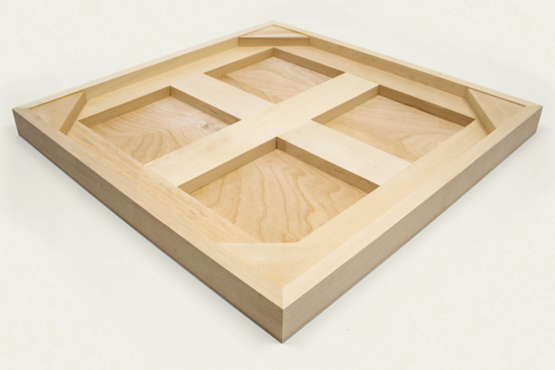 A wooden geometric shaped tray with open compartments, placed on a white surface.