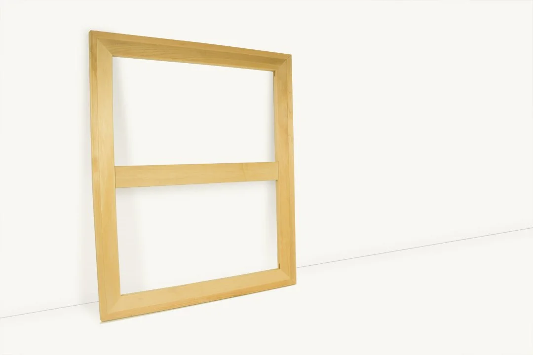 A wooden picture frame with two horizontal bars, leaning against a white wall.