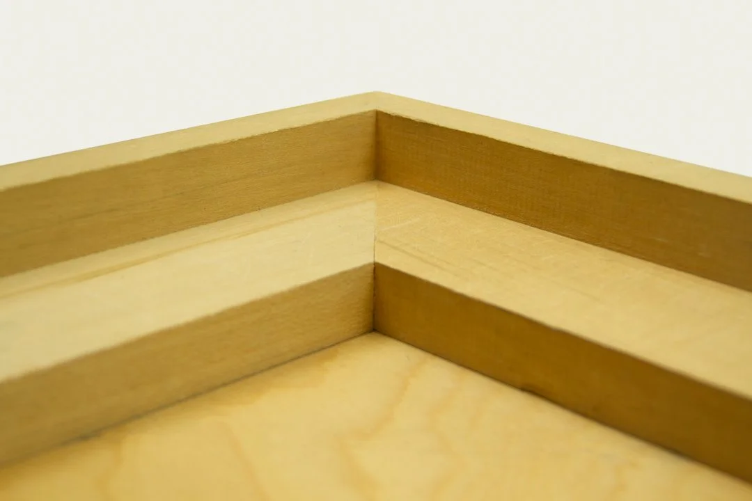 Close-up of a corner of a wooden surface and a wooden frame or molding.