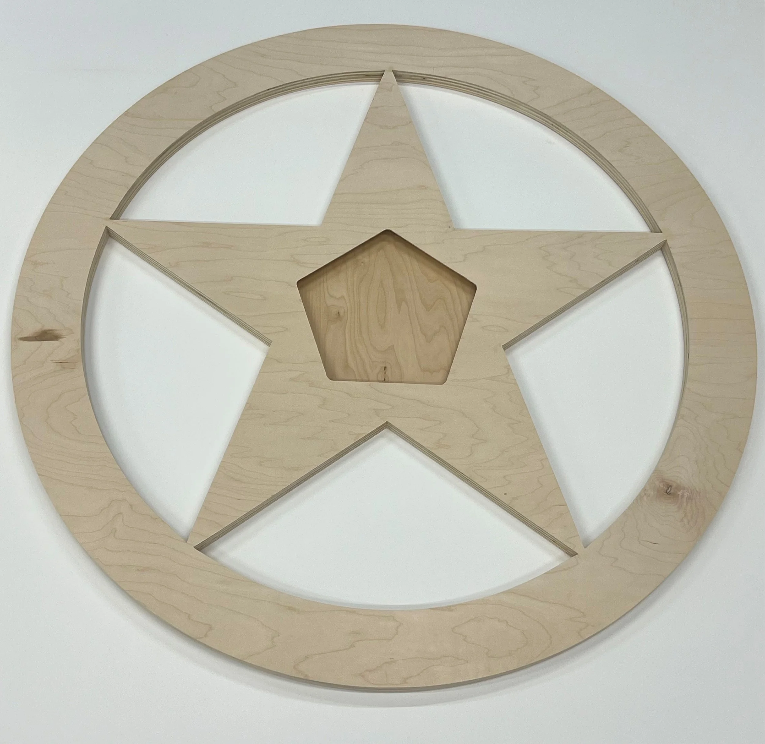 Wooden star shaped art panel with a central star cut-out, with a 5-way hanging channel cleat inset into the middle, laying on a white surface.