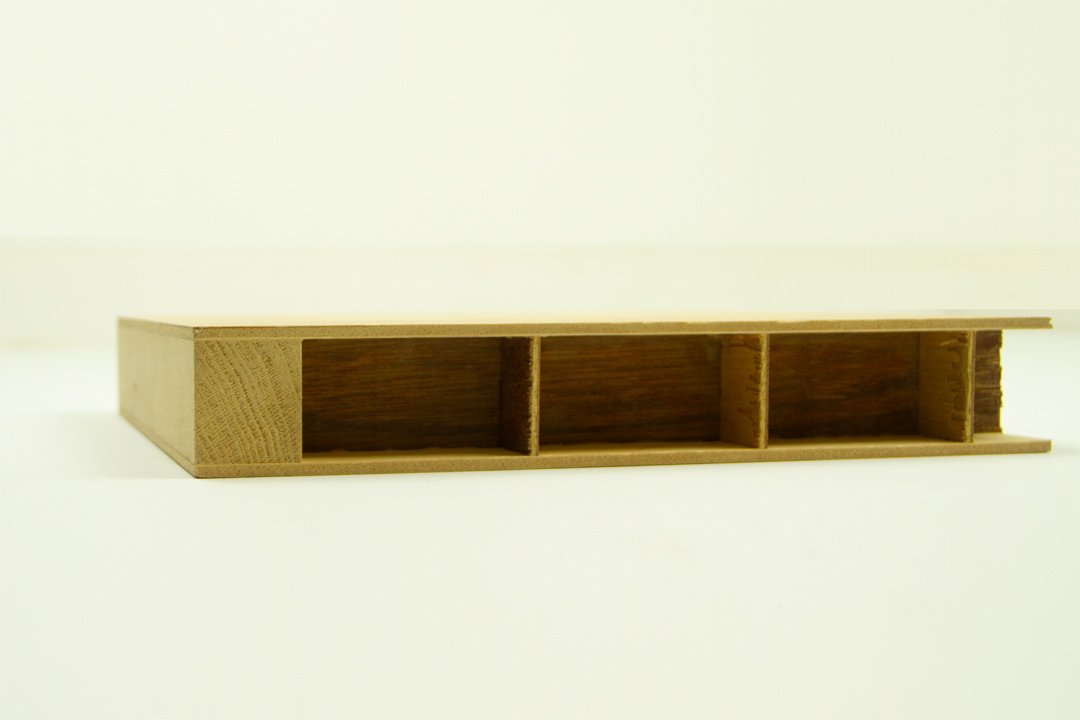 A wooden rectangular object with four internal compartments, placed on a white surface with a white background.