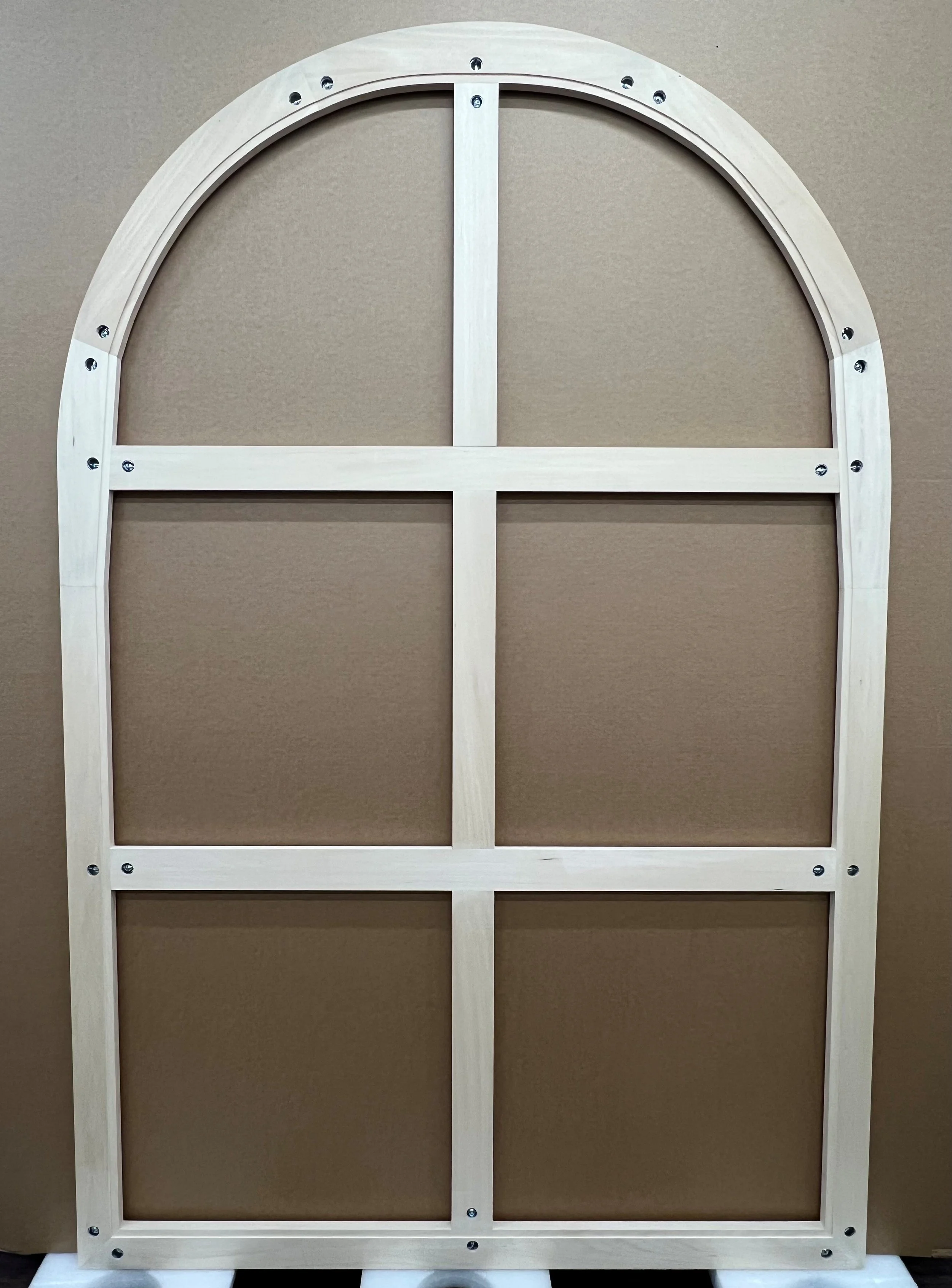 A wooden art stretcher shaped in a arch specifically to template for an antique painting resting on cardboard.