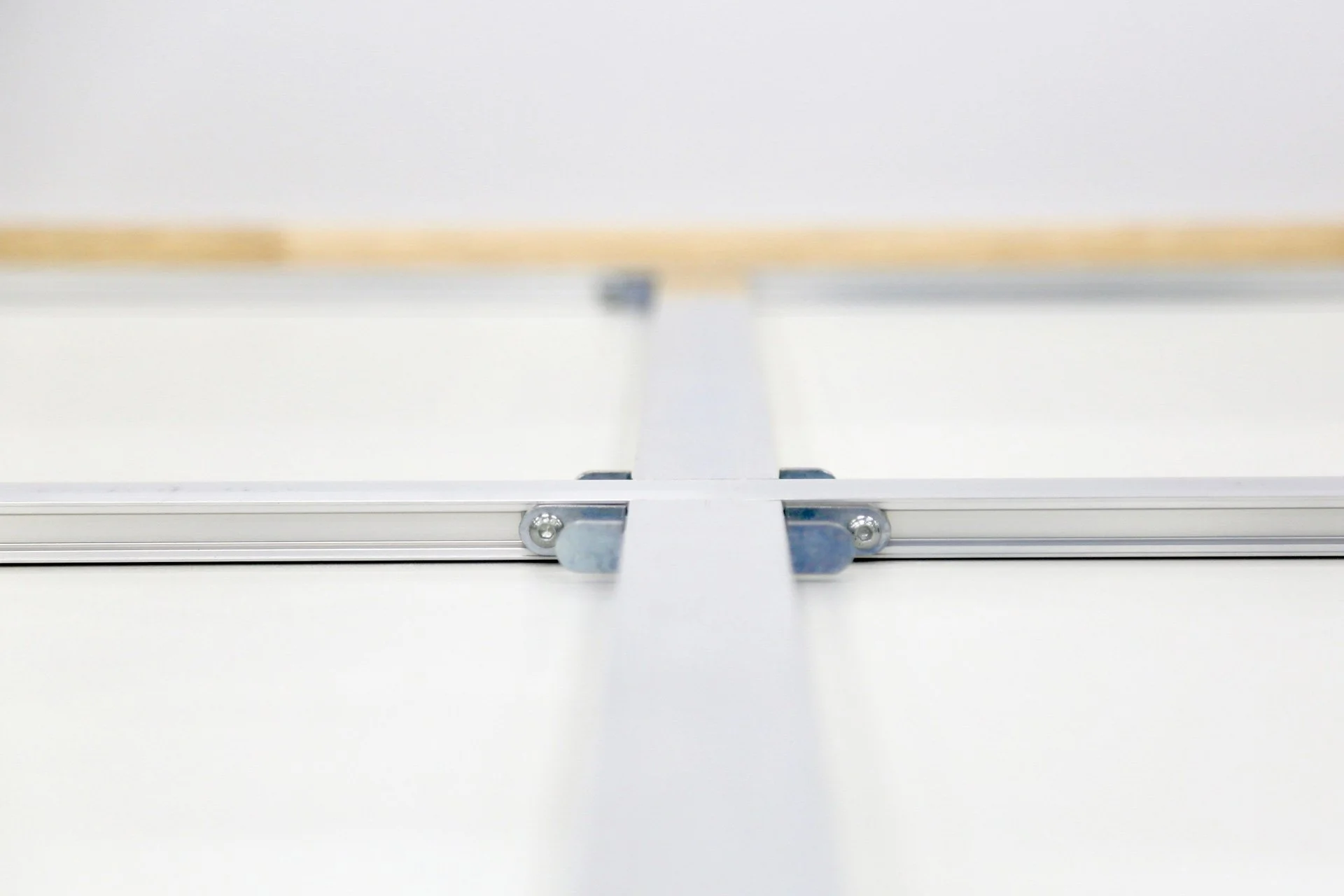 Close-up of a metal hinge and bracket attached to a white surface, with screws securing the parts.