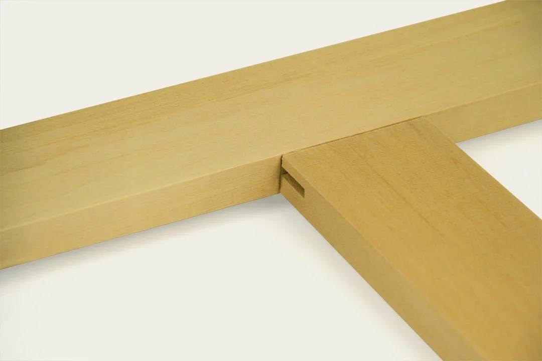 Close-up of two wooden pieces joining together with a slot joint on a white surface.
