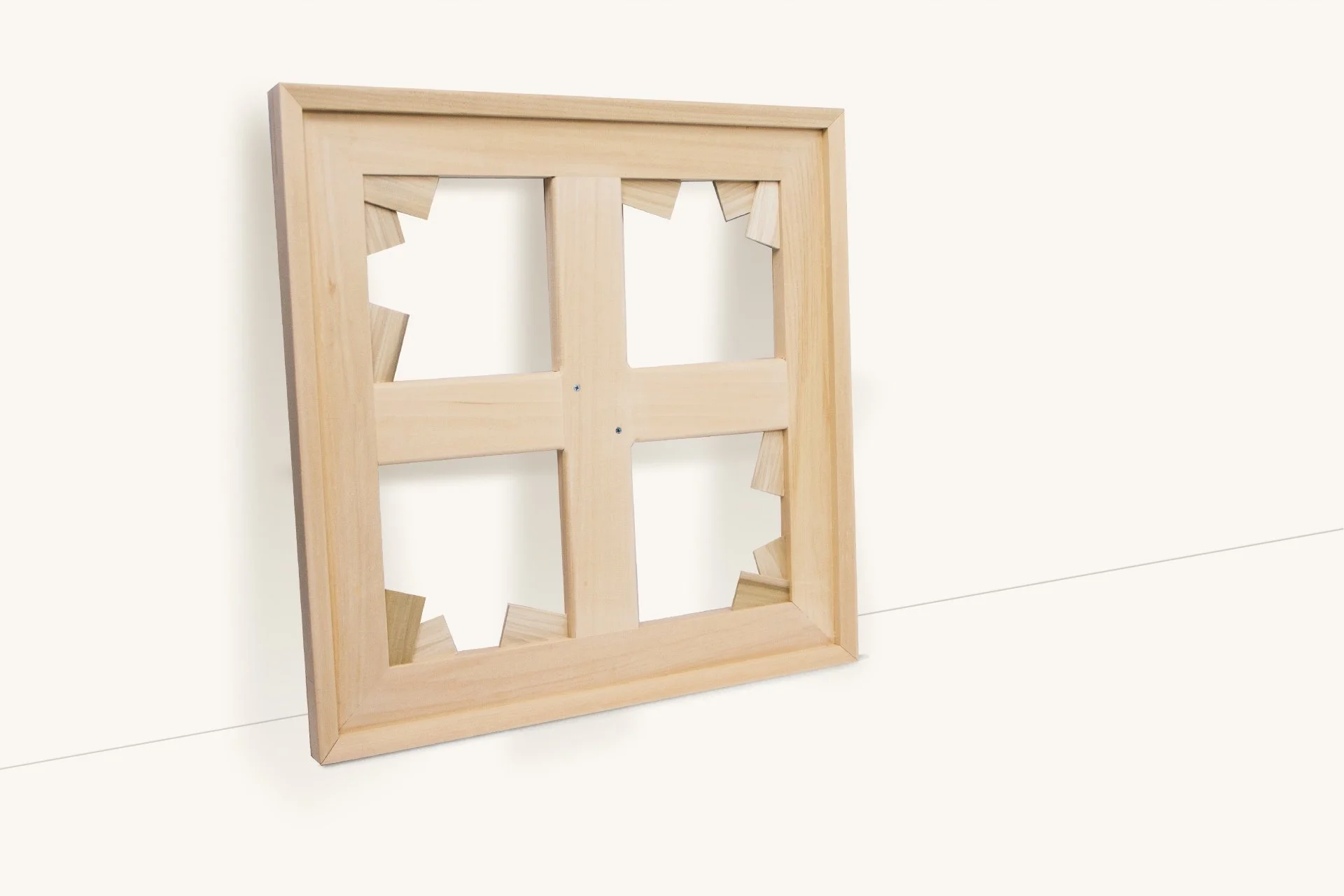 Wooden frame with geometric cutouts leaning against a white wall.