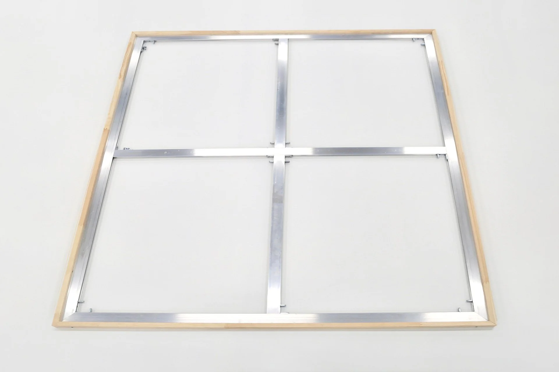 Metal frame structure with wood border on a white wall, possibly for a large display or partition.