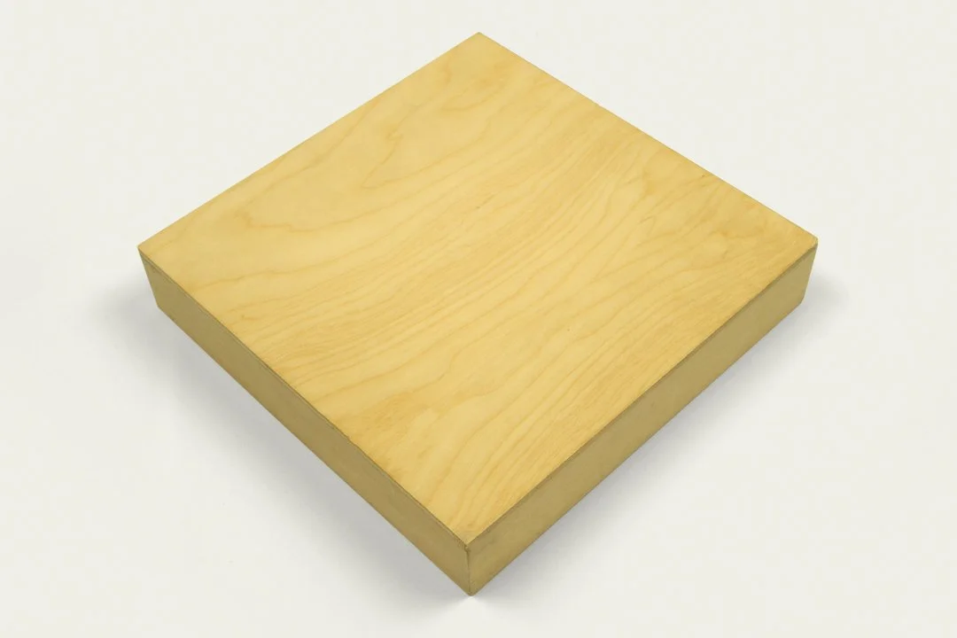 A light-colored wooden block with a smooth surface and slightly beveled edges sits on a plain white background.