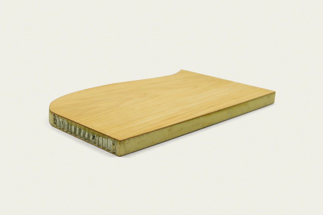 Shaped aluminum honeycomb panel with a wooden veneer, on a white background.