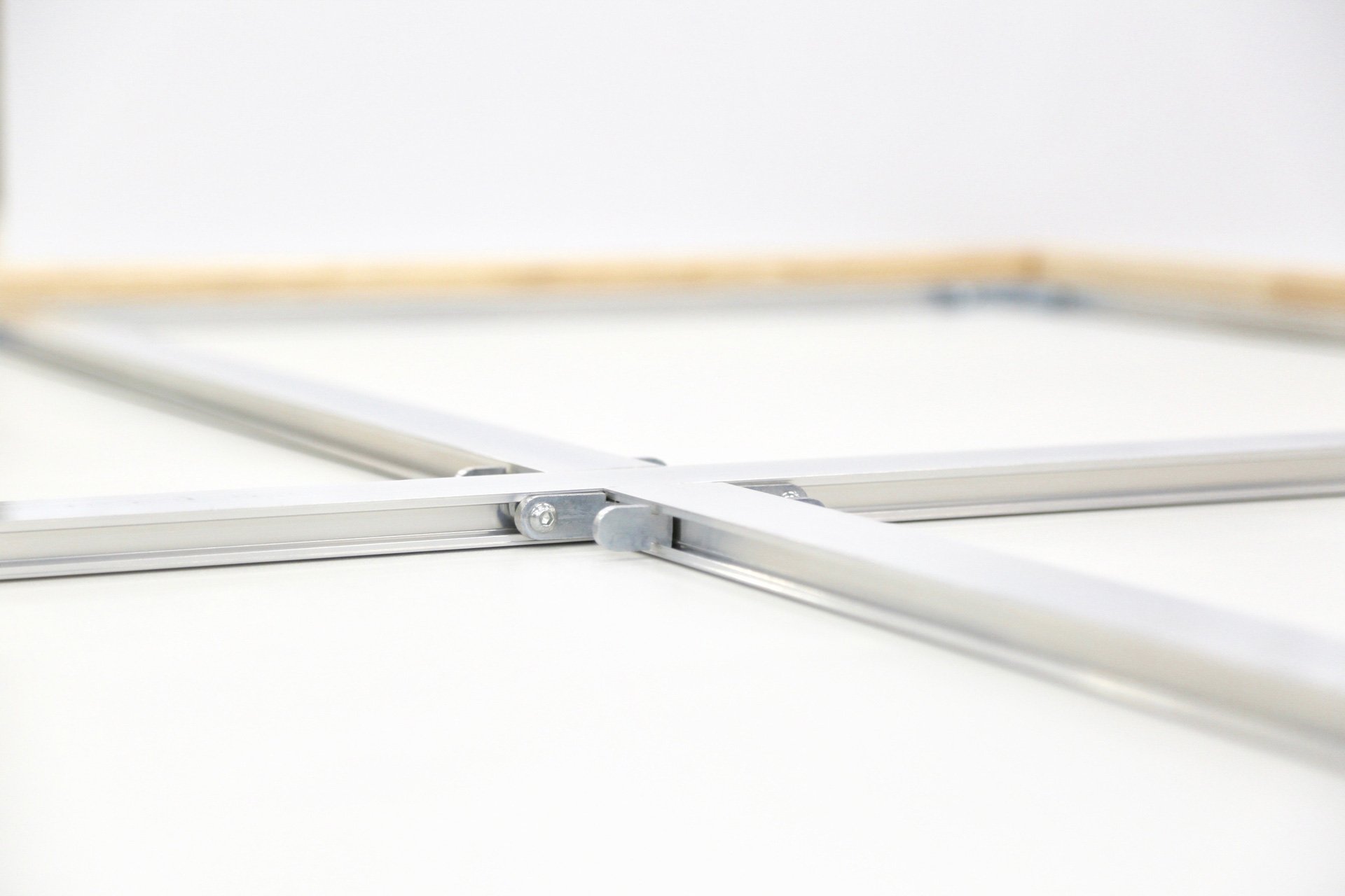 Close-up of a metallic sliding mechanism on a white surface, possibly part of a framing or sliding door system.
