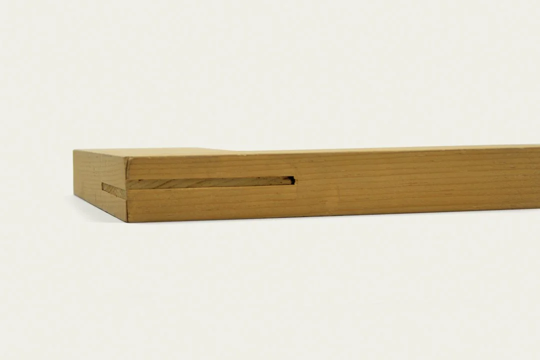 A close-up of a wooden frame piece with a groove and a notch, possibly part of furniture or a construction component, against a plain white background.