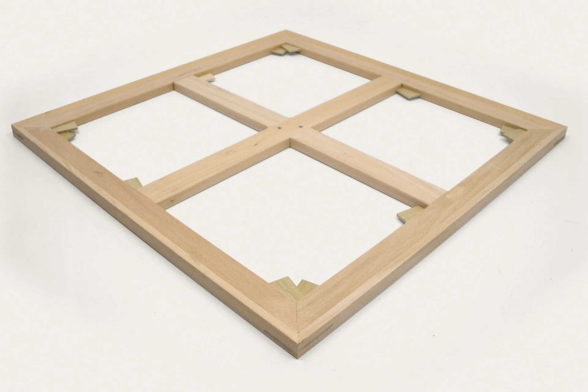 A wooden frame on a white surface, consisting of two large squares with smaller inner frames, held together by small wooden clips.