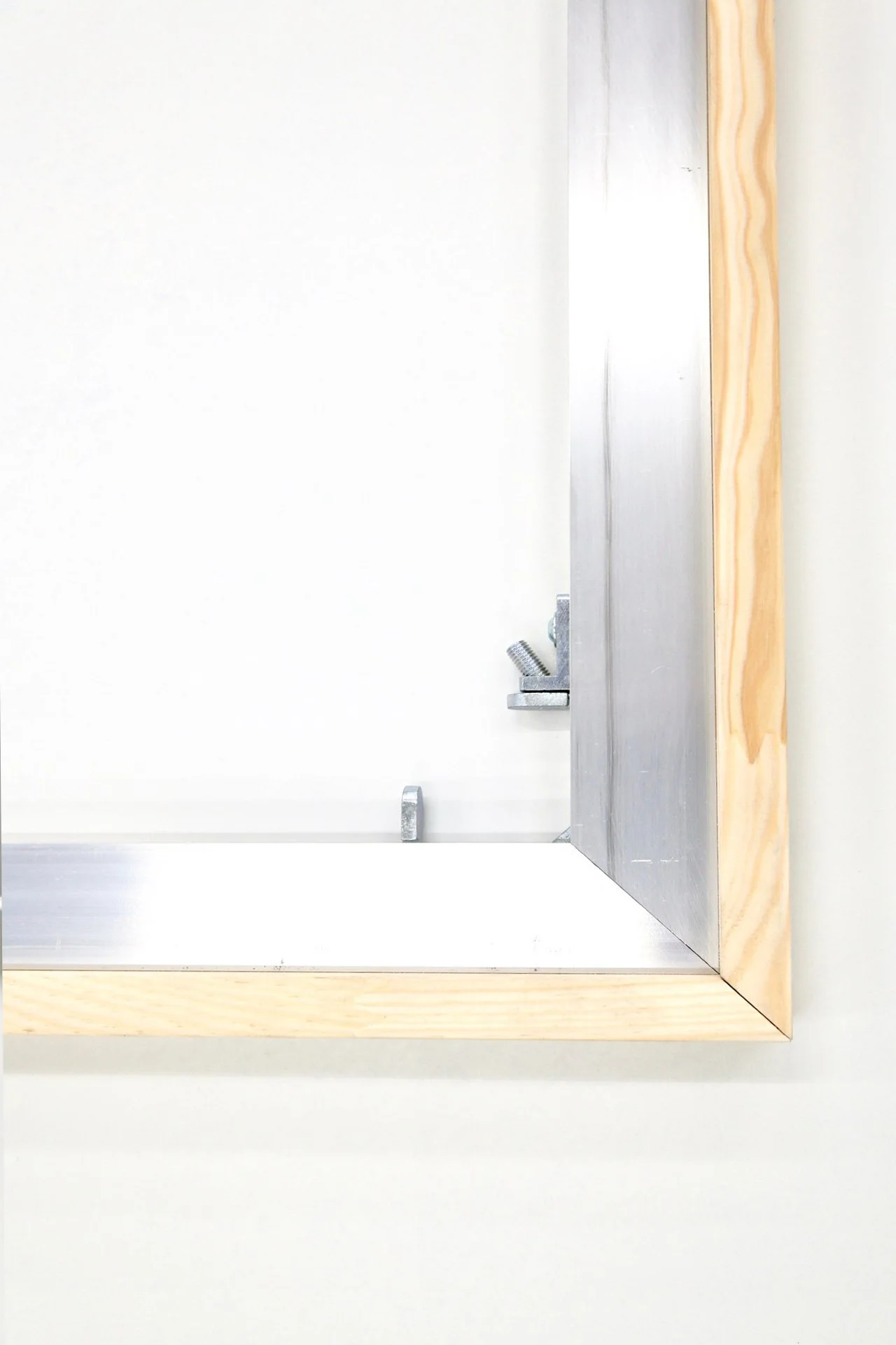 A close-up of a metal and wood frame, focusing on the corner where the aluminum stretcher can be keyed out. Simon Liu, Inc fine art supports.