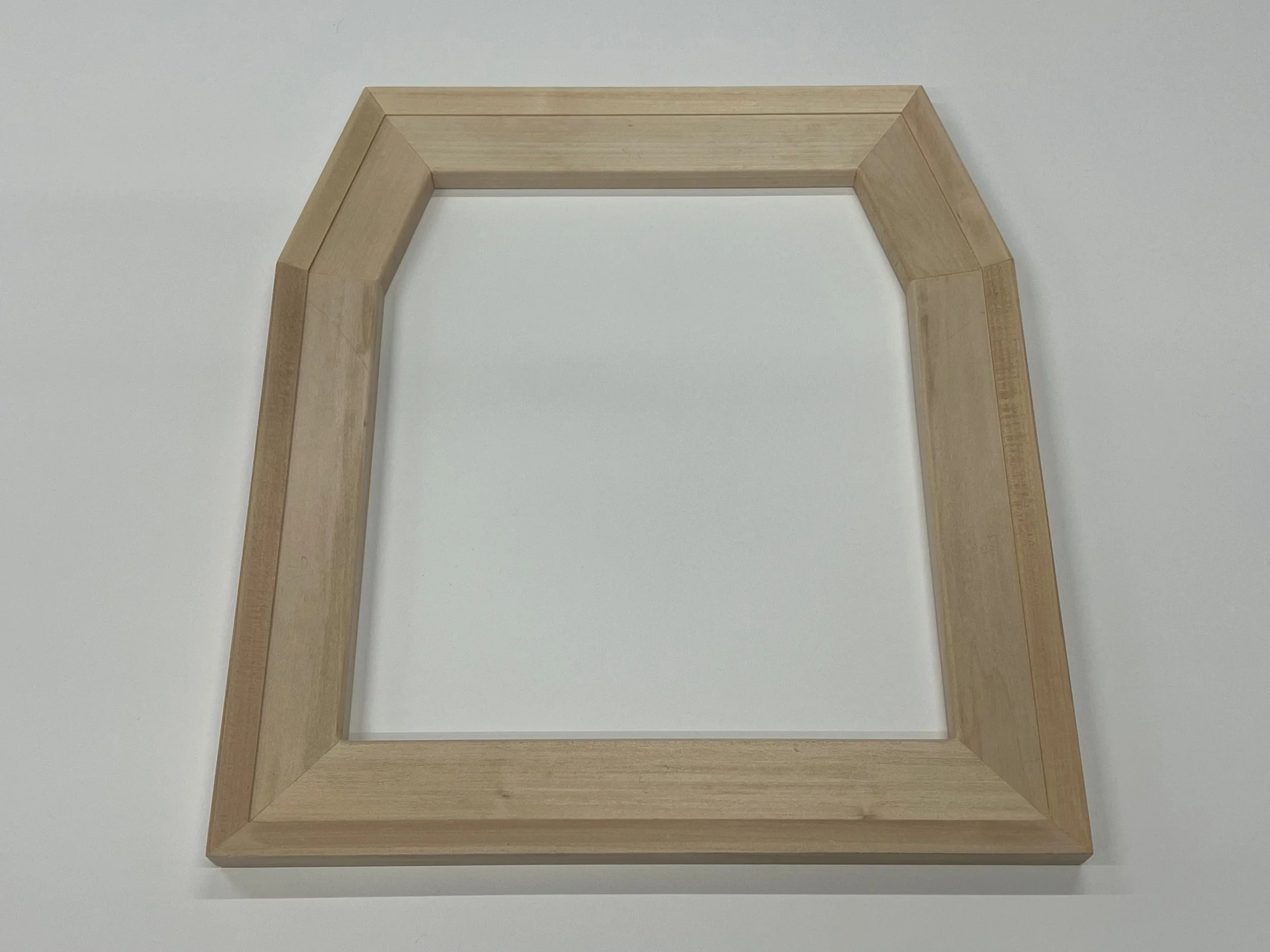 A wooden picture frame lying flat on a white surface.