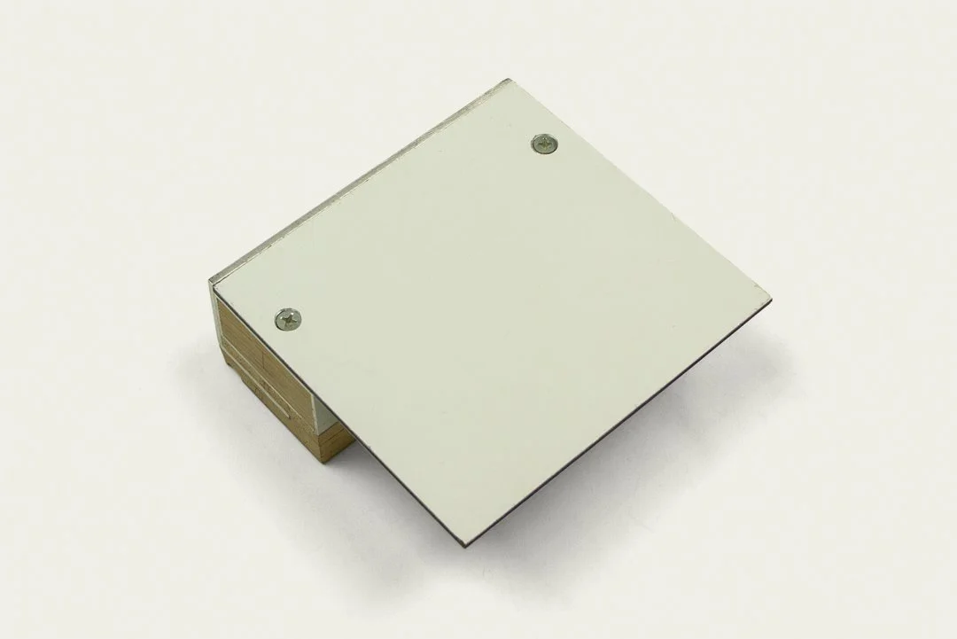 A small rectangular metallic box with two screws on the top, placed on a white surface.