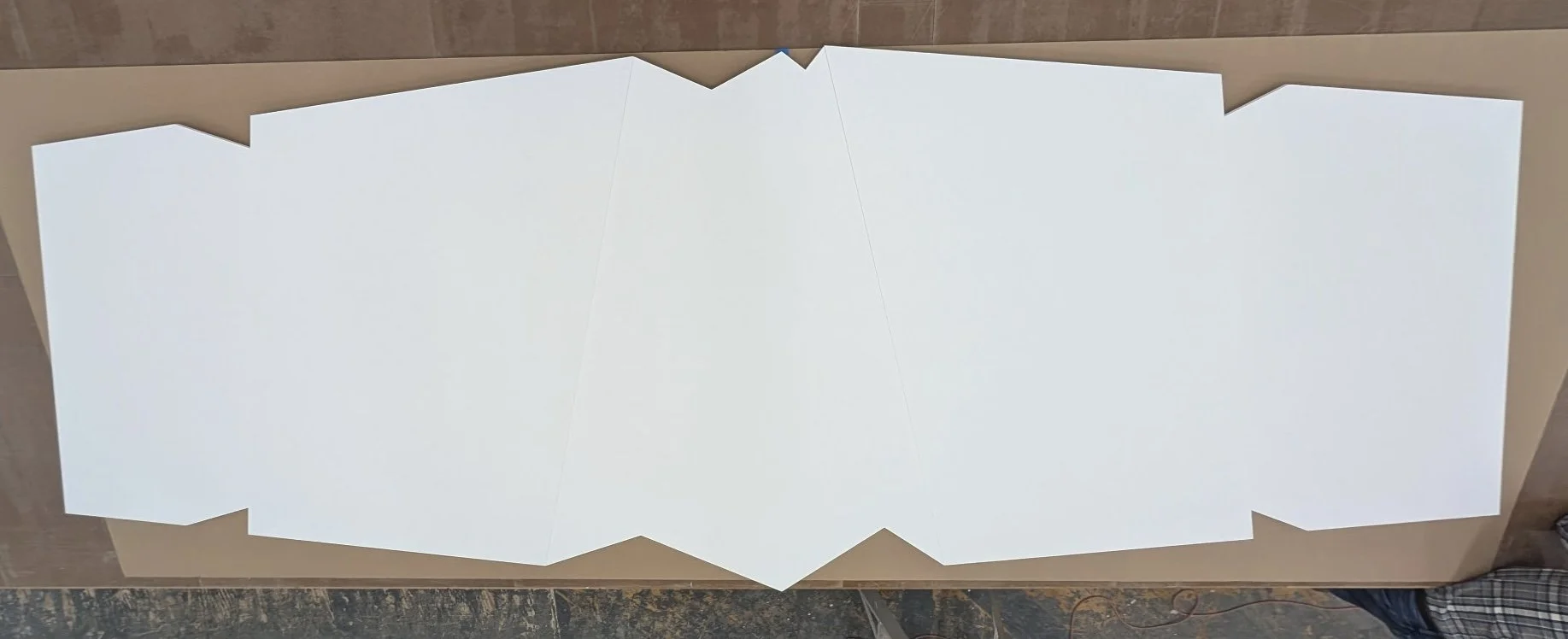 A large unfolded white paper on a wooden table with angular edges.