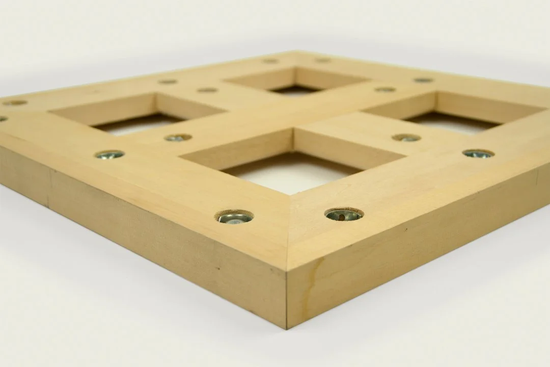 A wooden frame with multiple rectangular cutouts and visible metal screws.