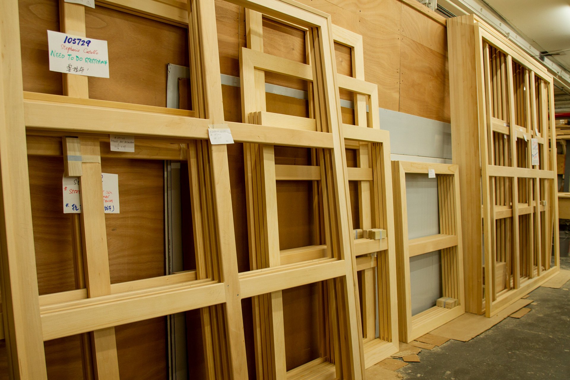 Store showing multiple wooden window frames stacked against the wall.