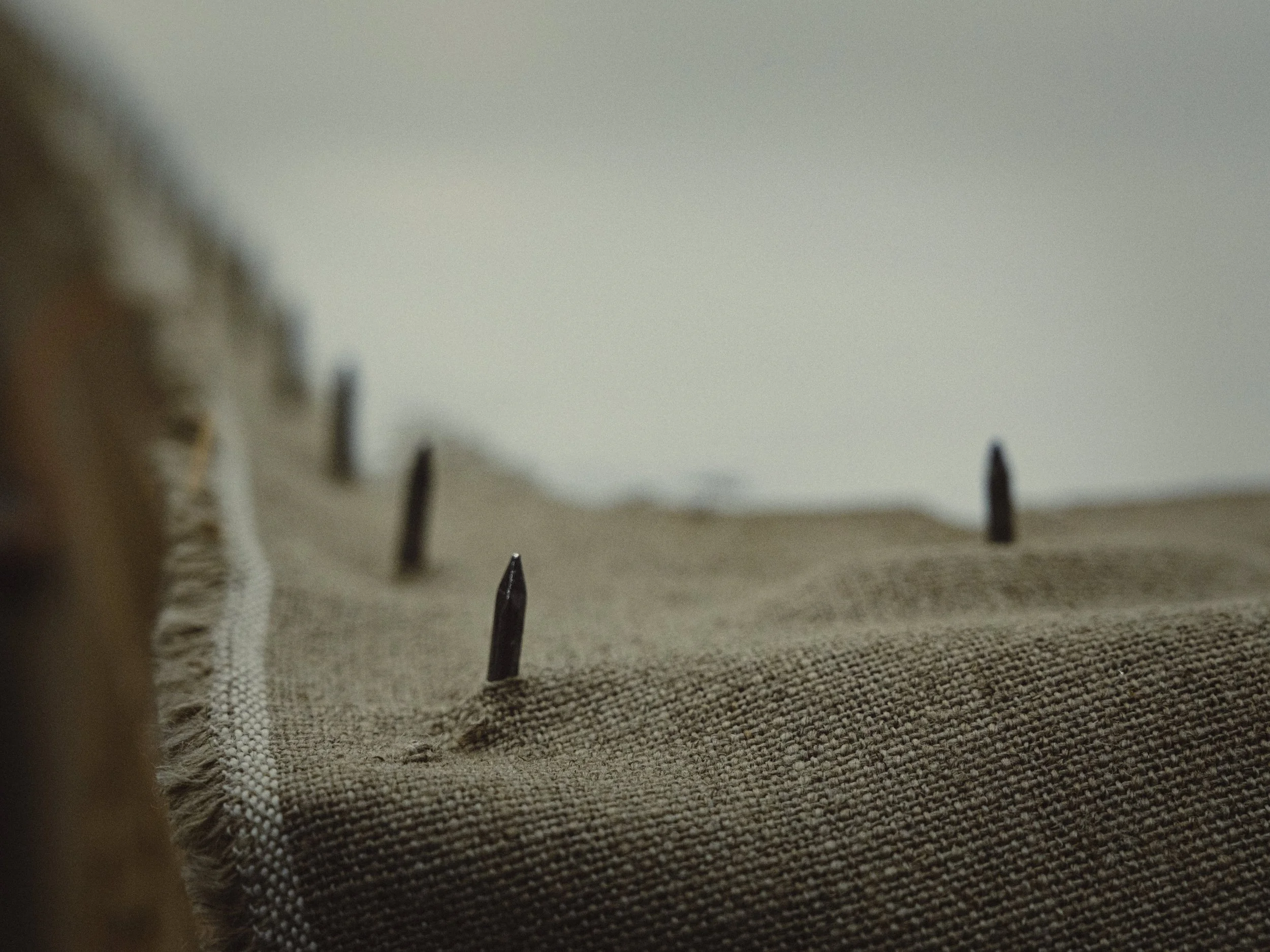 Close-up of thick linen fabric surface pre-primed by hand on a stretched rack.