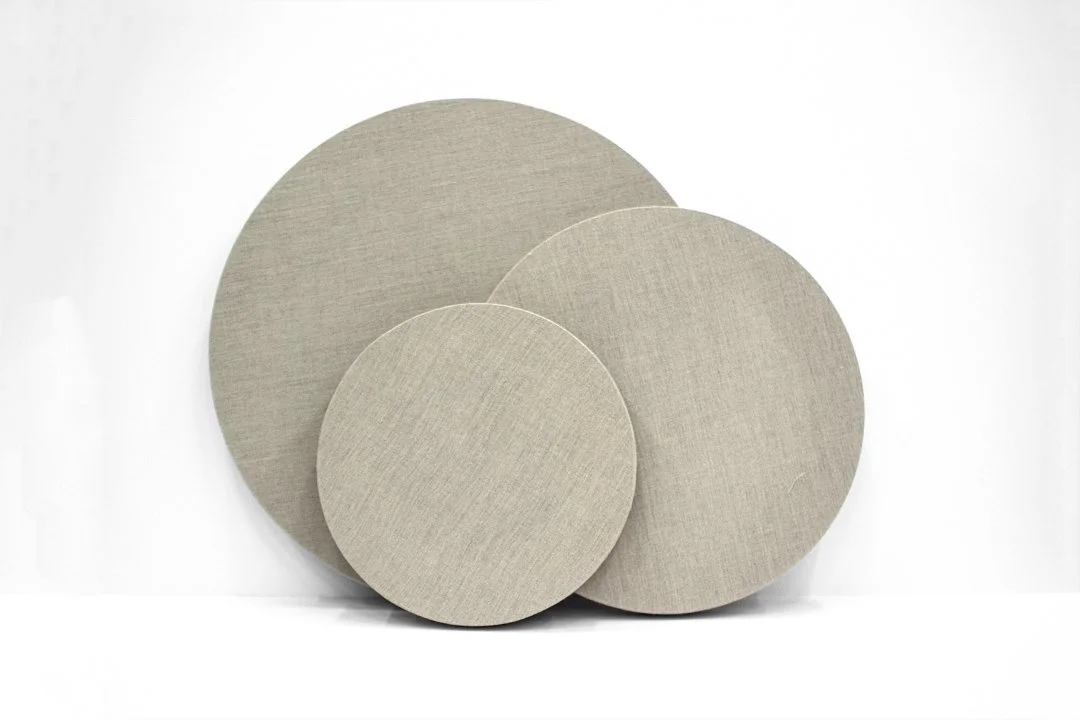 Three round beige fabric-covered acoustic panels of different sizes stacked together on a white background.