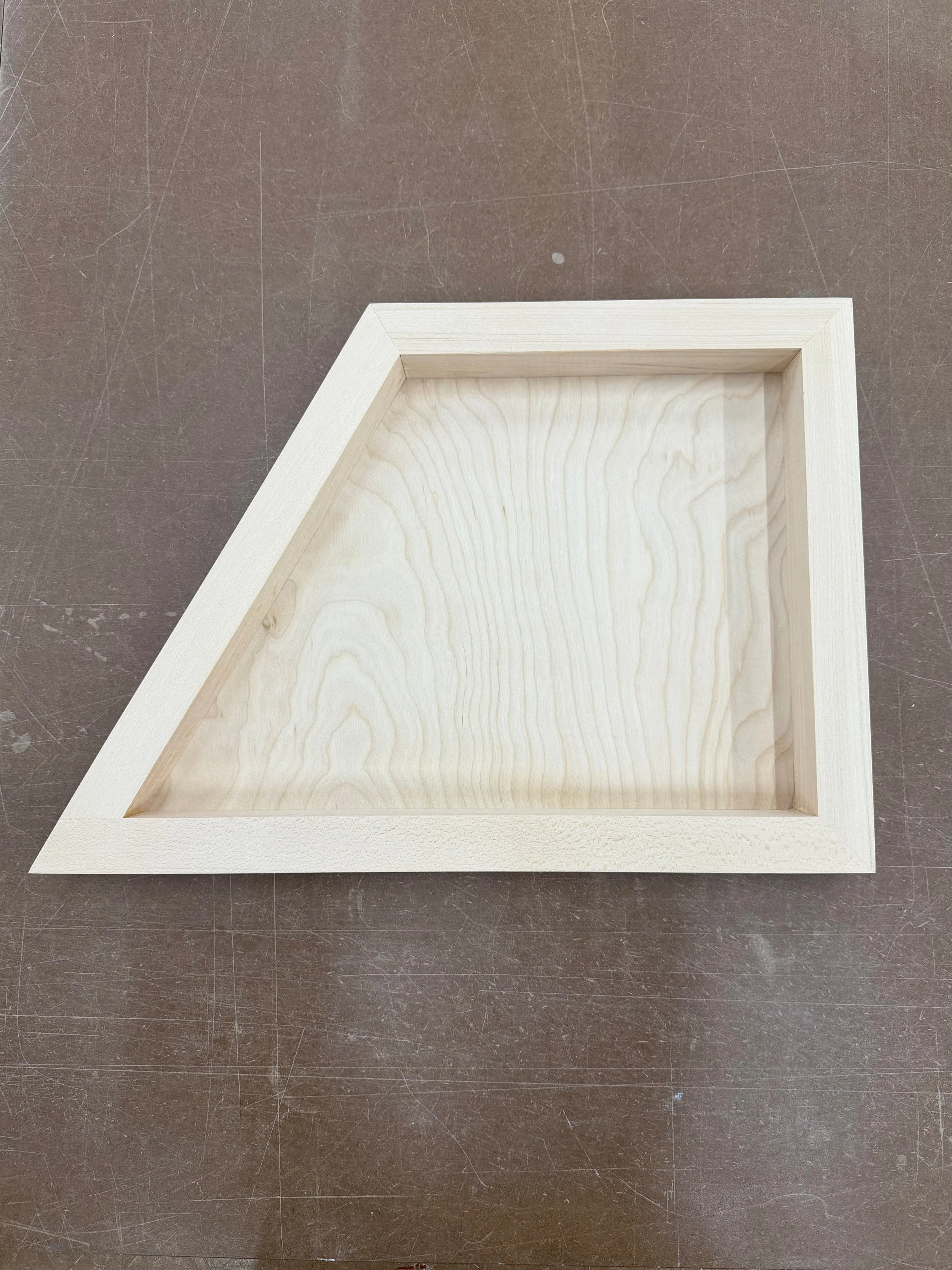 Wooden fine art panel trapezoid on a brown work surface.