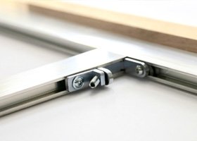 Close-up of adjustable metal hinges attached to a white edge, likely part of a piece of furniture or a structure.