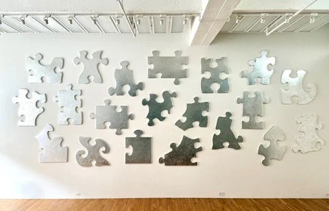 Various puzzle pieces scattered on a light-colored wall.
