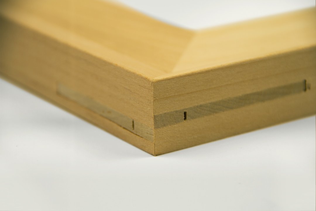Close-up of a wooden picture frame corner showing miter joint and small nails