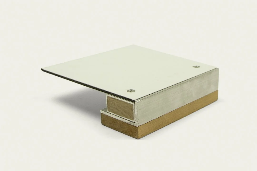 A small rectangular metal and wood object with a flat top, appearing to be a mount or bracket, placed on a plain white background.