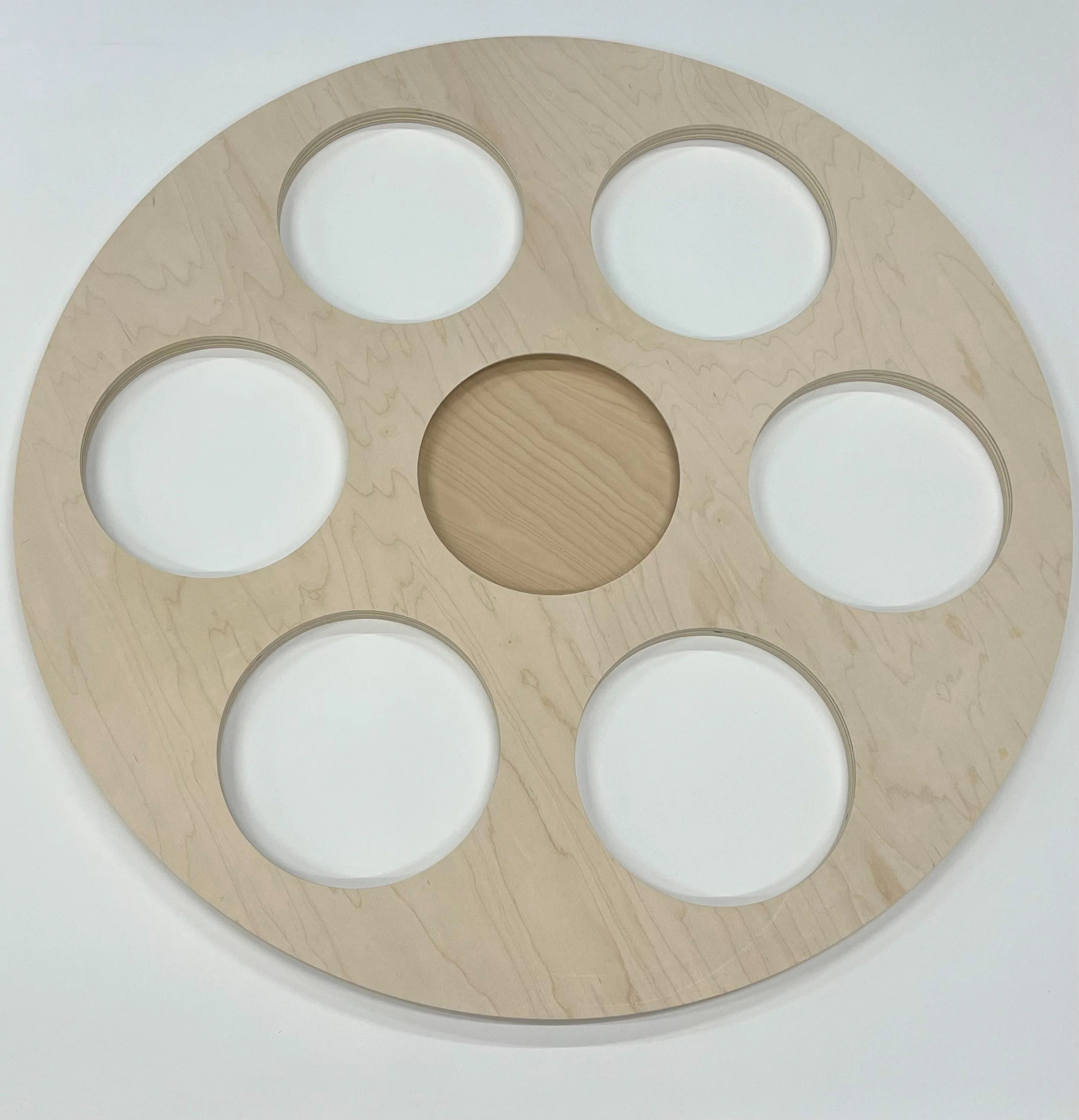 A circular wooden object with multiple concentric rings and openings, placed on a white surface.