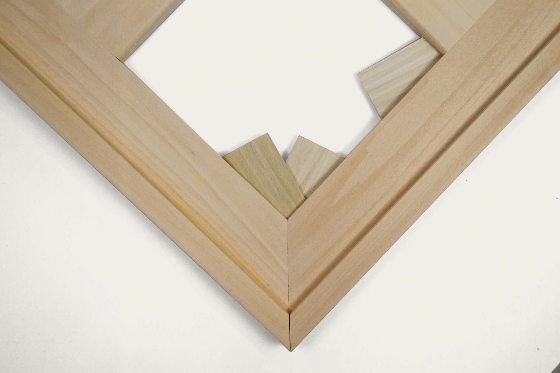 Close-up of a wooden picture frame with mitered corners, placed on a white surface.