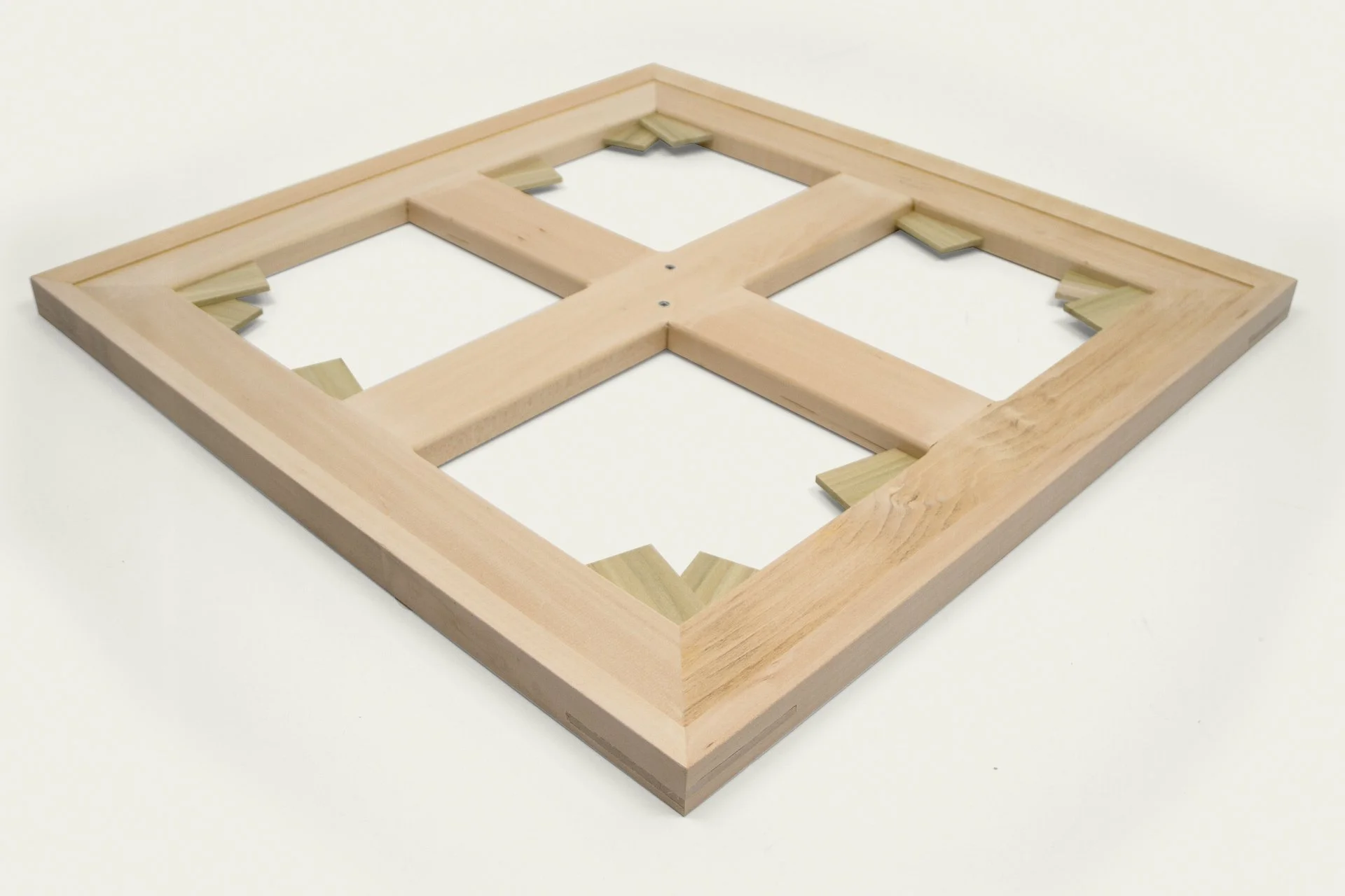 A wooden frame with internal support brackets, lying on a white surface.