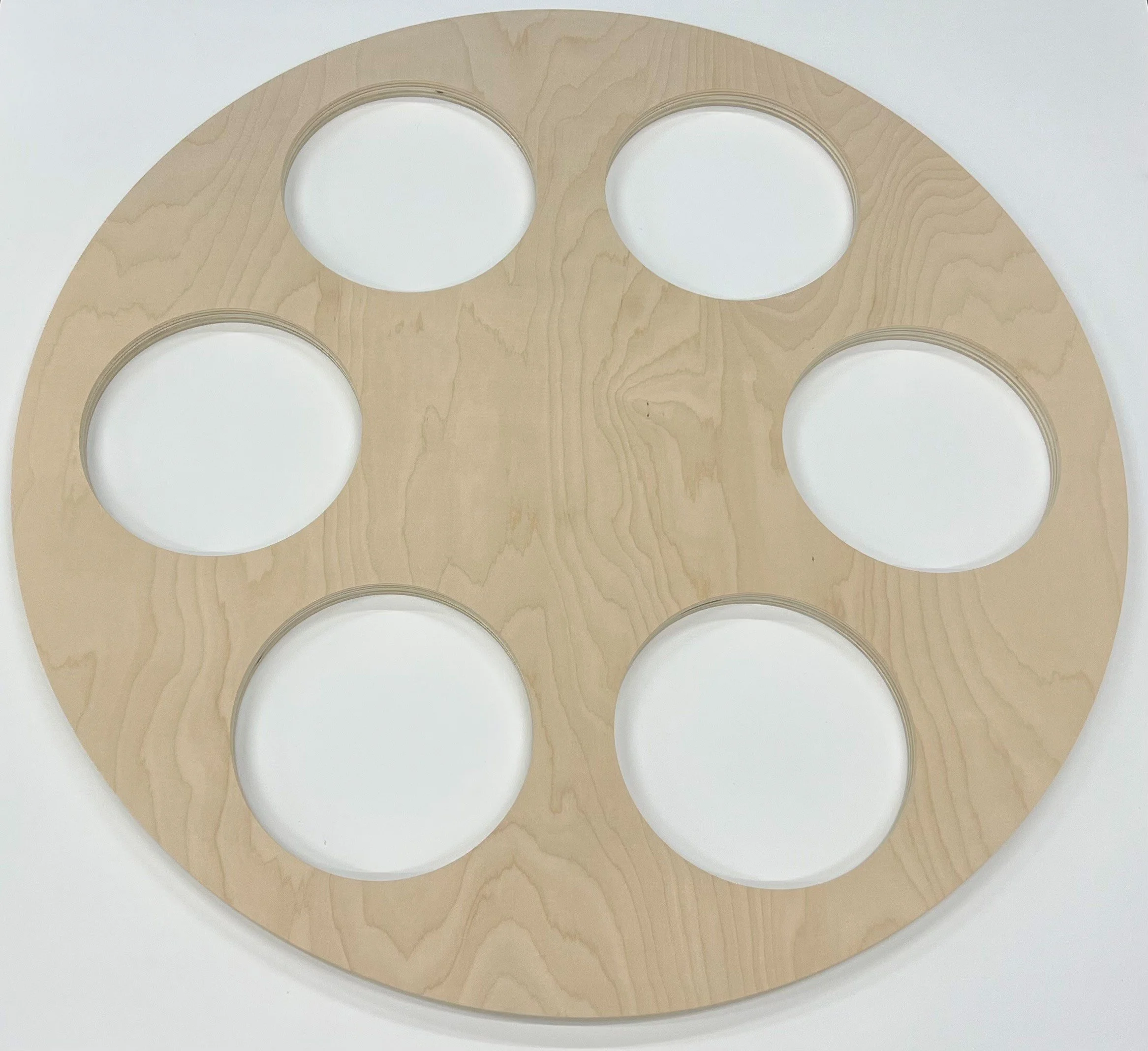 Wooden circular craft piece with multiple round cutouts.