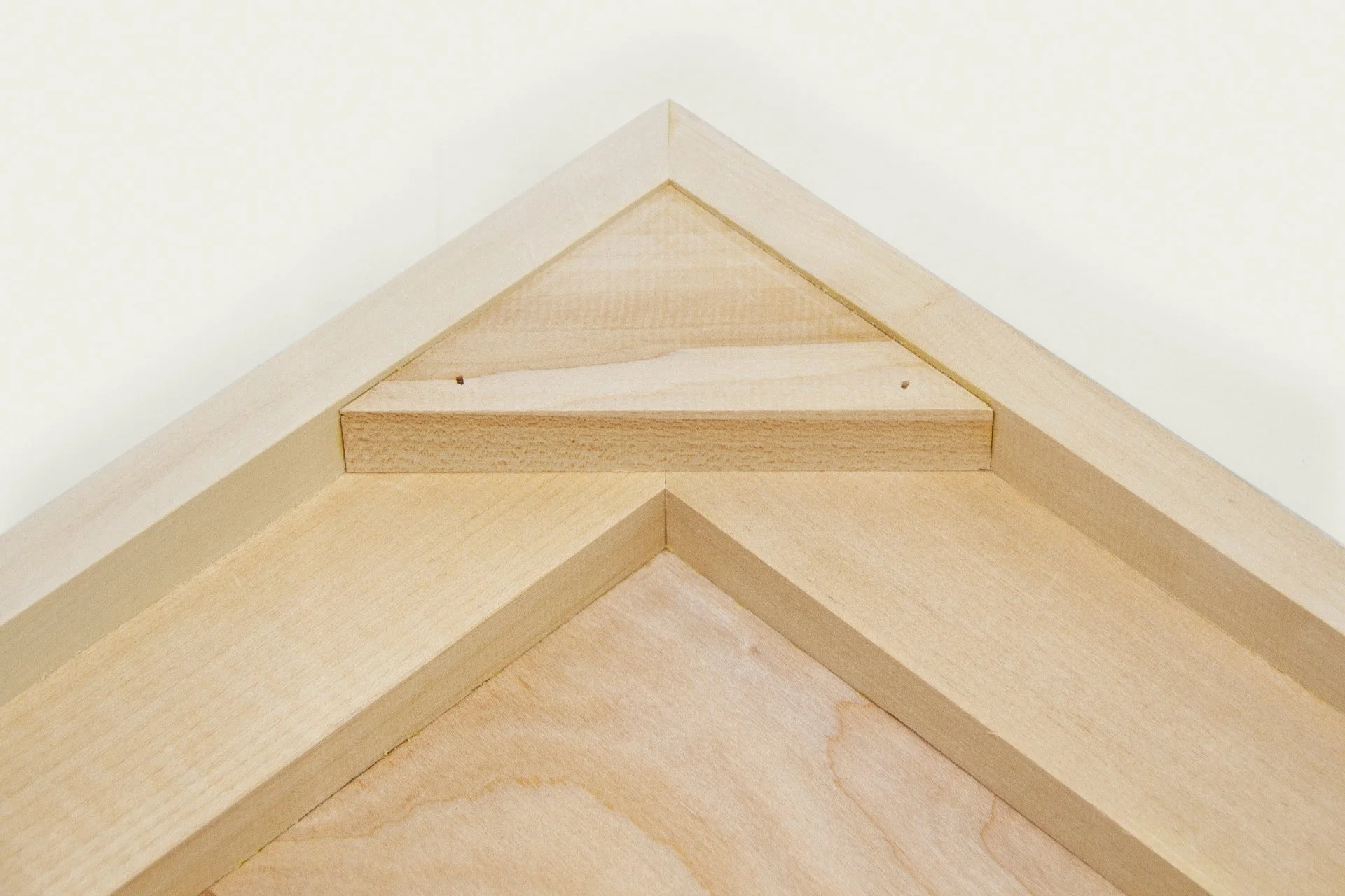 Close-up of a wooden corner with angled overlapping boards, showing the texture and grain of the wood.