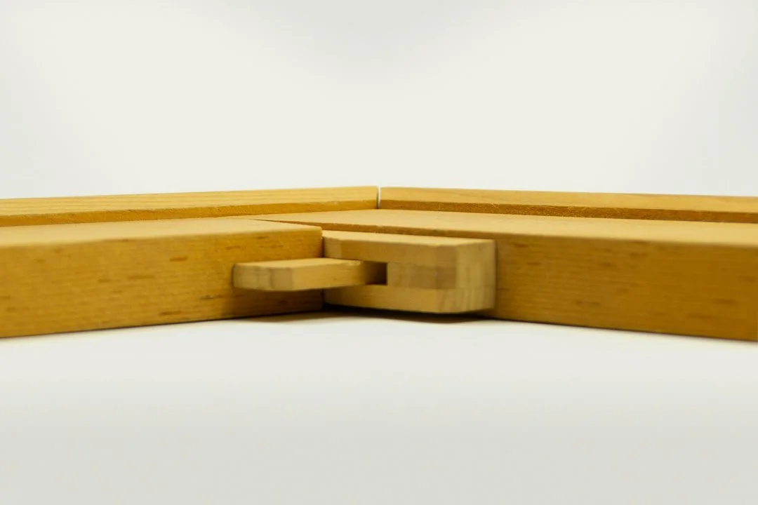 Close-up of a wooden corner connector connecting two wooden pieces, against a plain white background.
