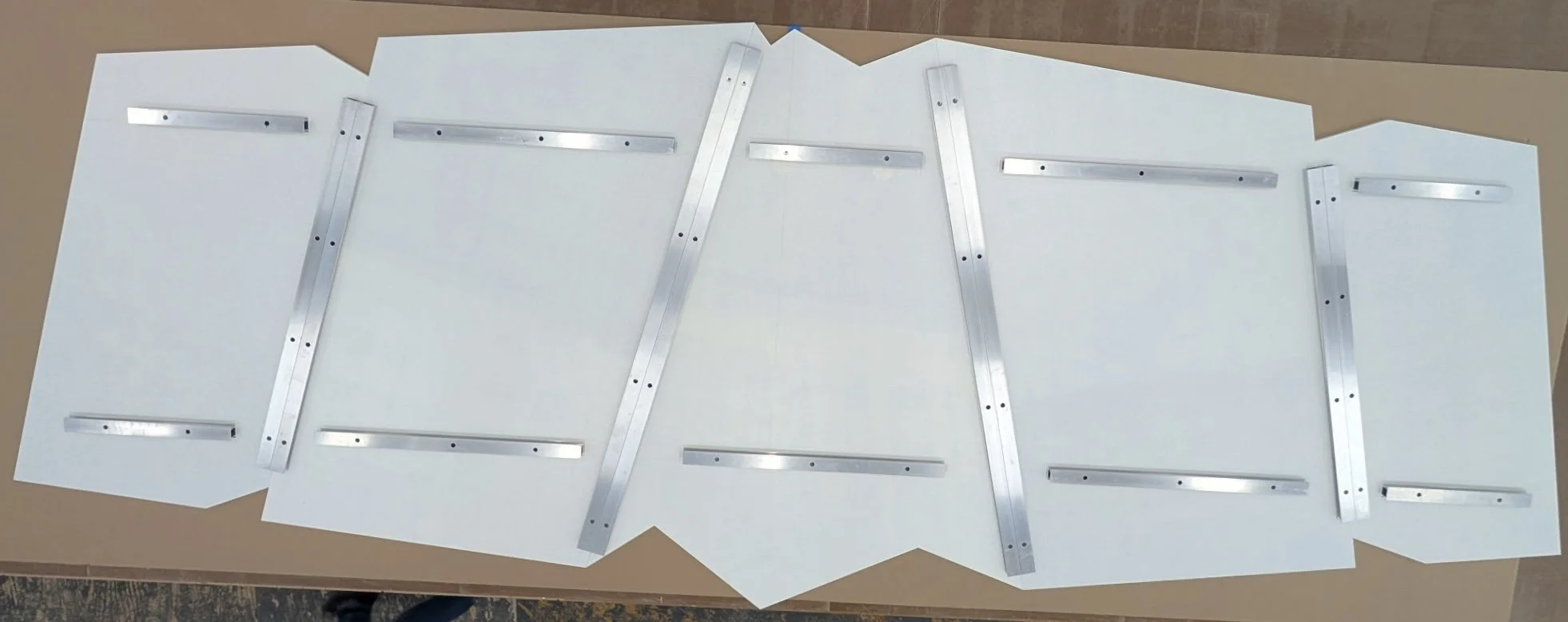 Several metal L-shaped and straight rulers arranged in an overlapping pattern on a white surface.