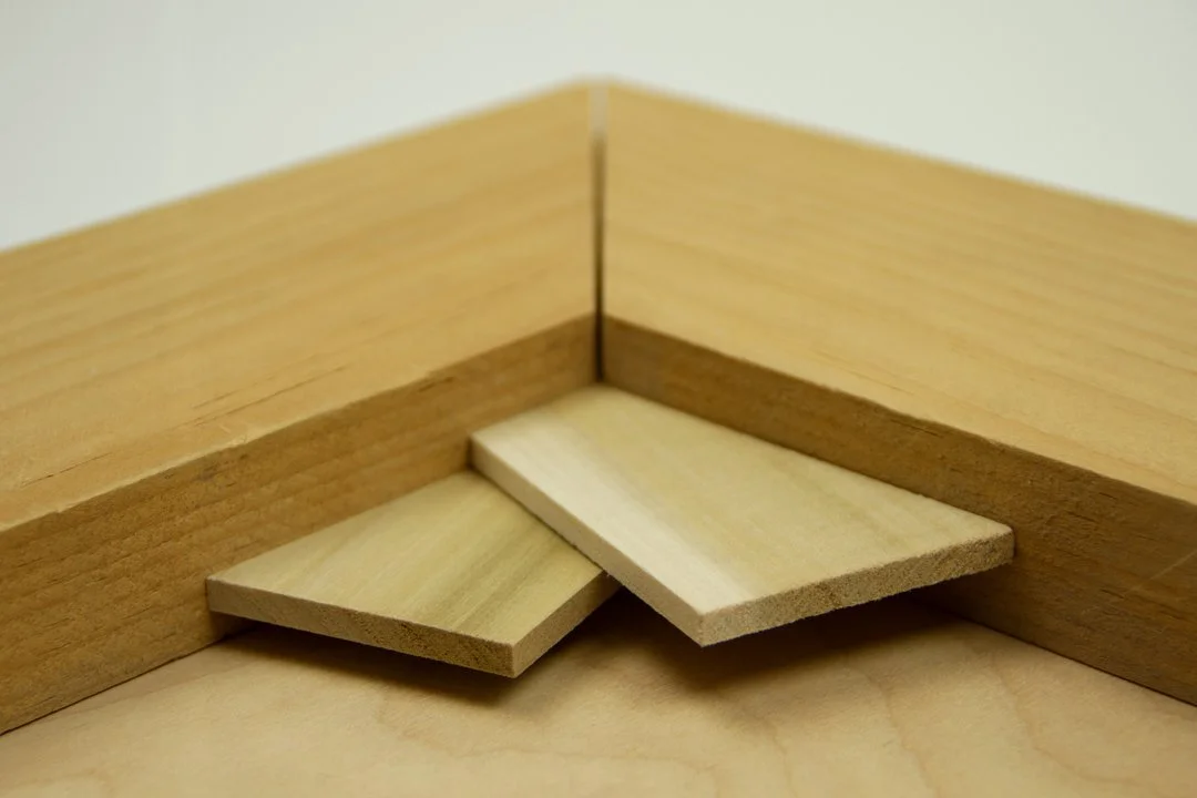 Close-up of wooden corner with two small wooden wedges used as shims or supports