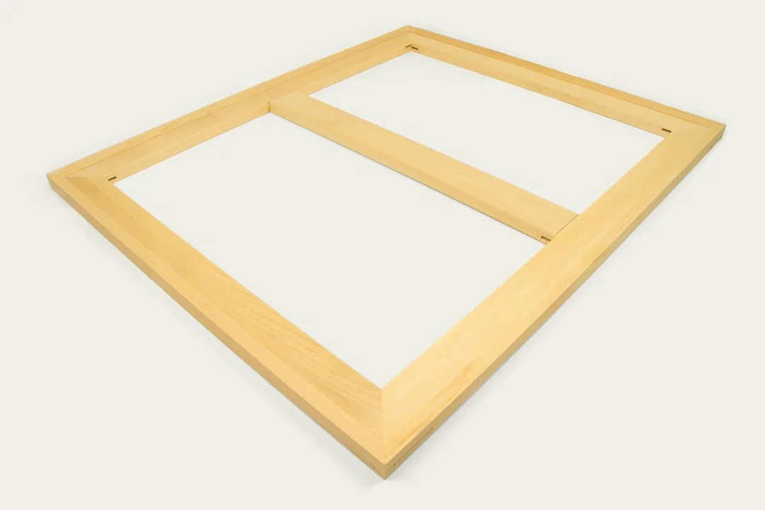 A wooden picture frame laying flat on a white surface.