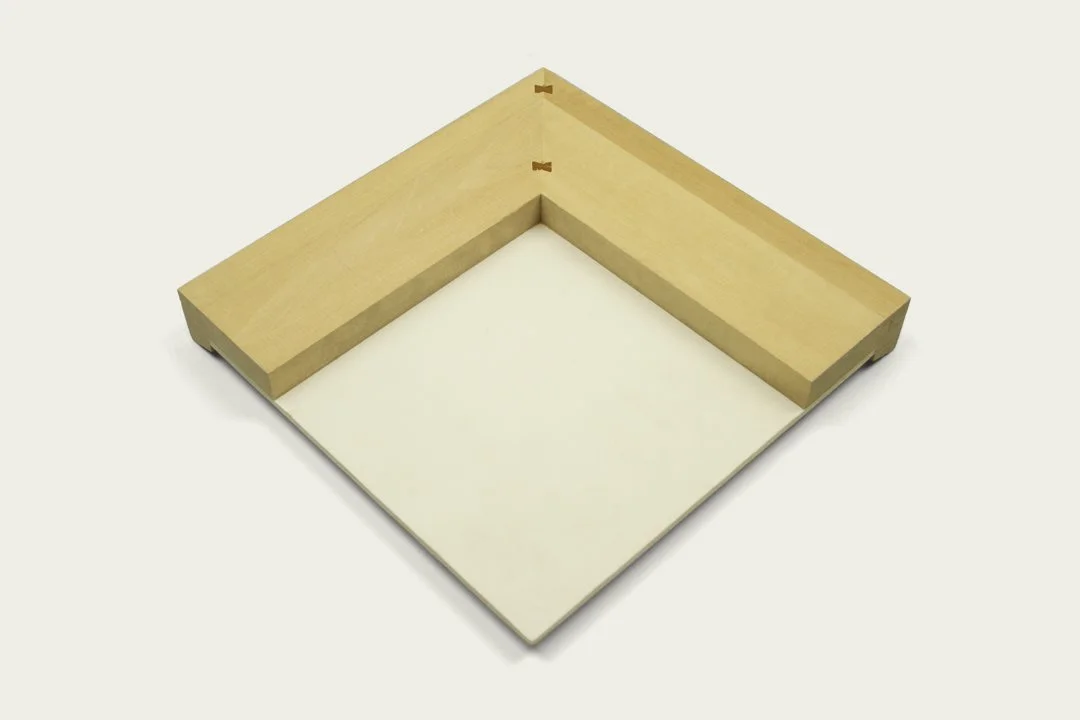Corner of a wooden Dibond art panel with a white backing board set against a plain light-colored background.