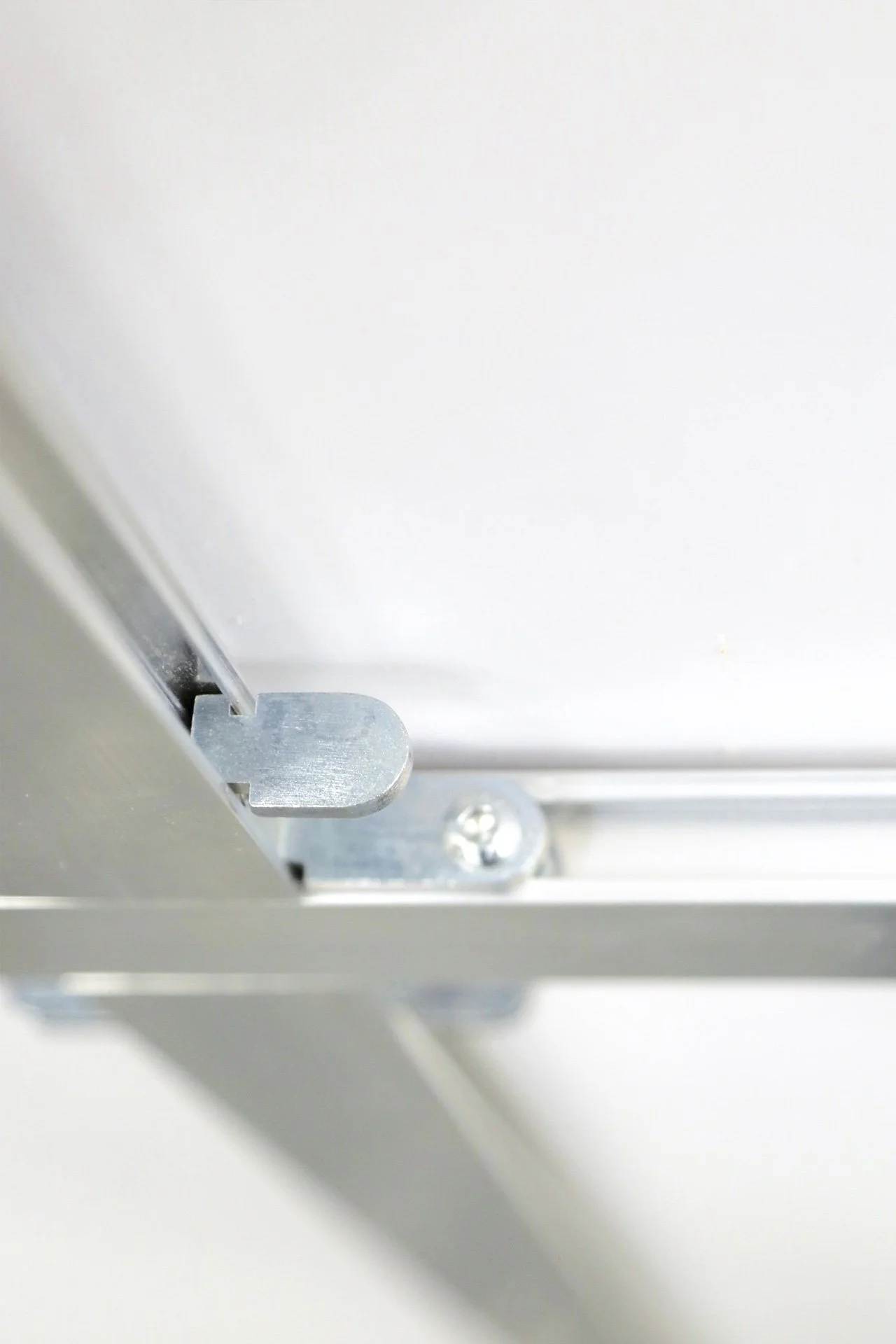 Close-up of a metal latch on a white surface, possibly part of a piece of electronic equipment or a machine.
