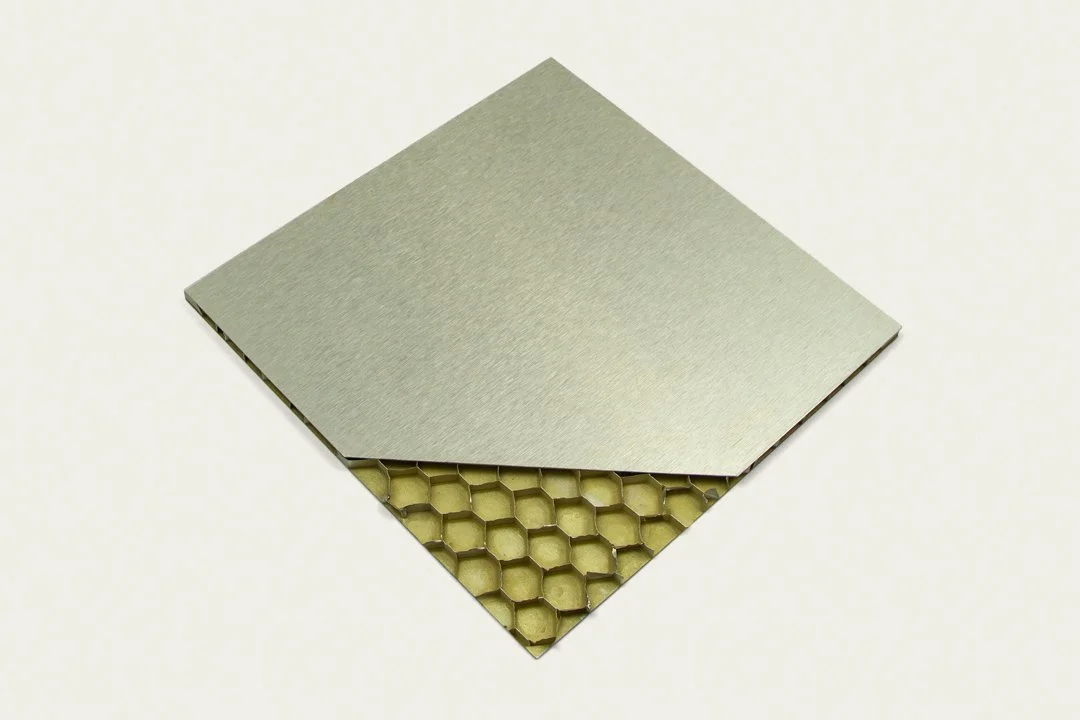 A metallic diamond-shaped panel partially covering a honeycomb structure.