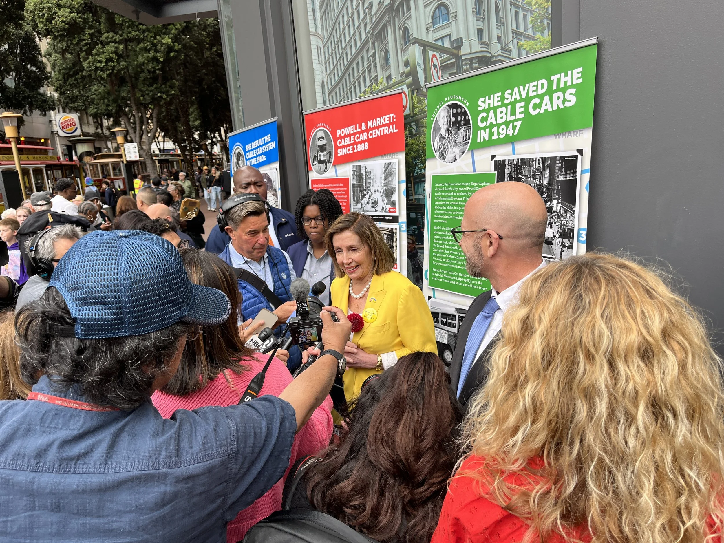 Nancy Pelosi holding two dahlias from the Dell during the Cable Car celebration.