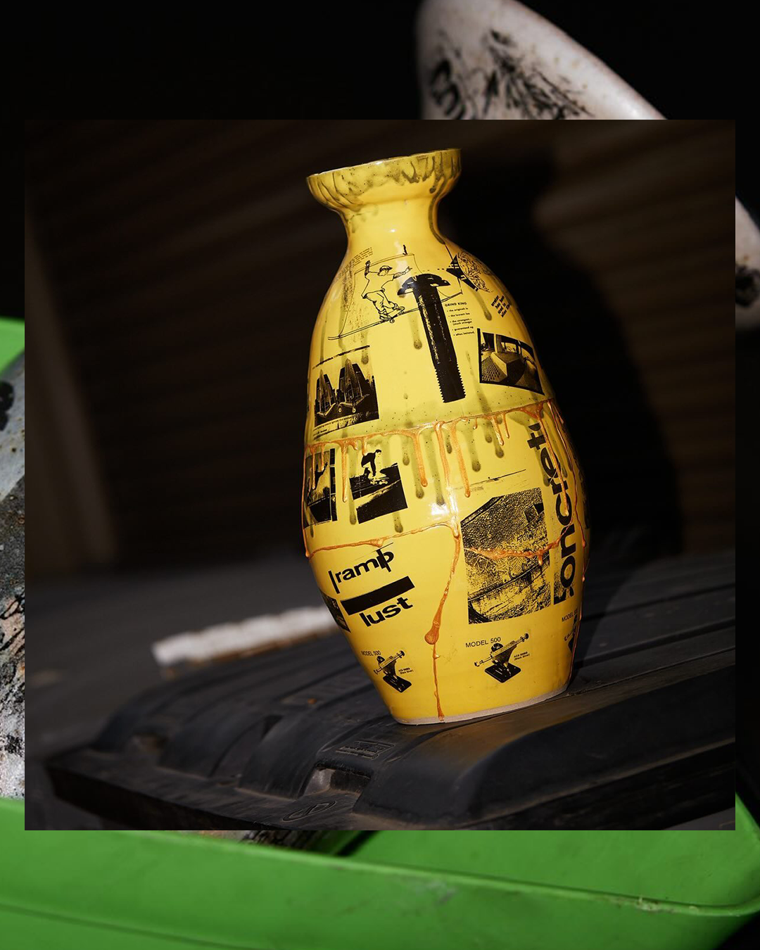 Yellow decorative vase with black graphic labels and text, resting on a black surface with a dark background.