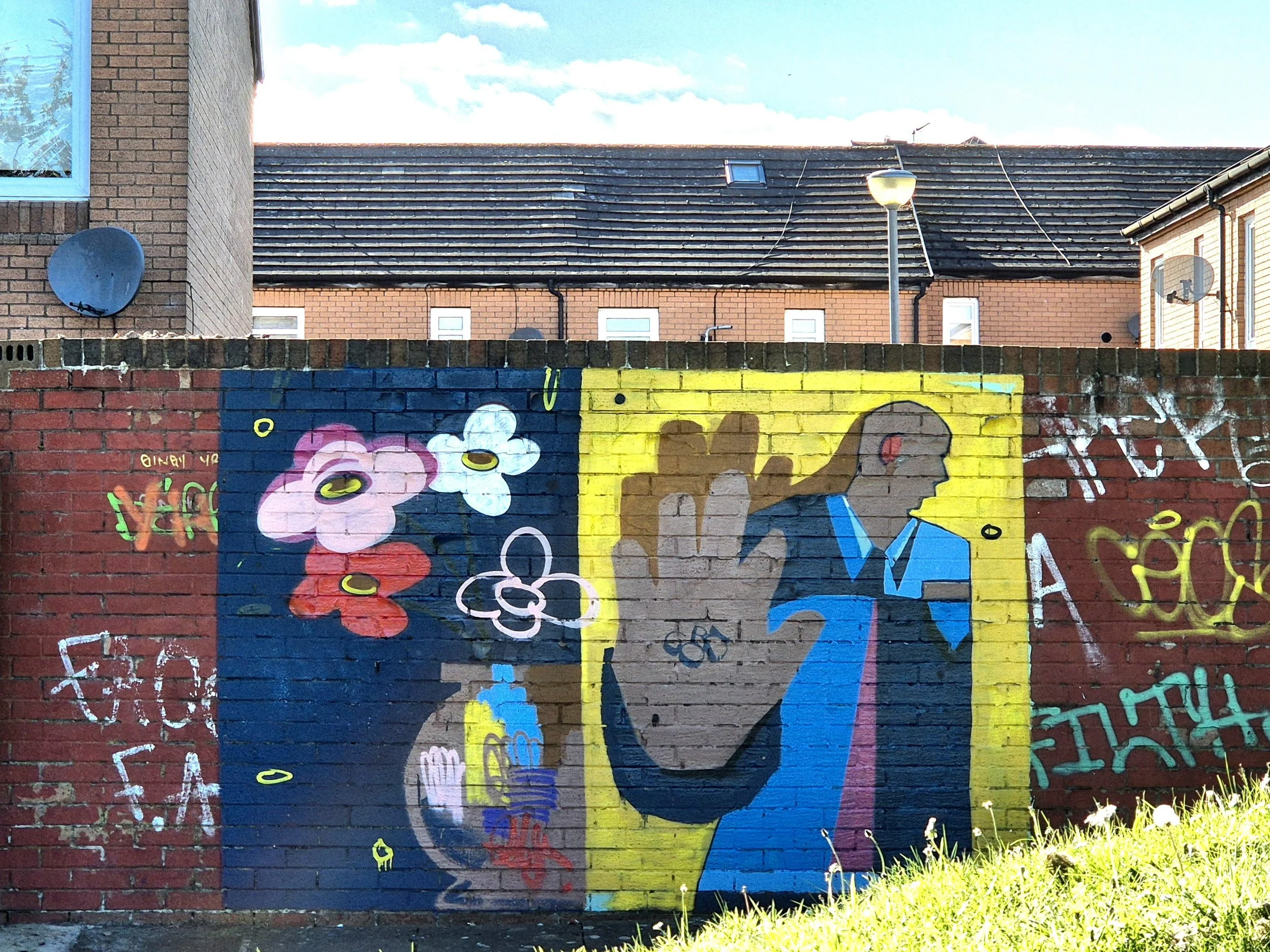A colorful graffiti mural on a brick wall features cartoonish characters, flowers, and abstract designs.